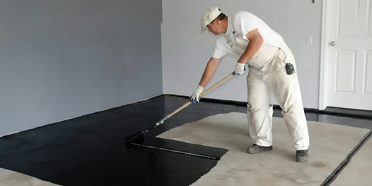 basement waterproofing professional applying waterproof coating to protect a basement floor in Indianapolis, IN